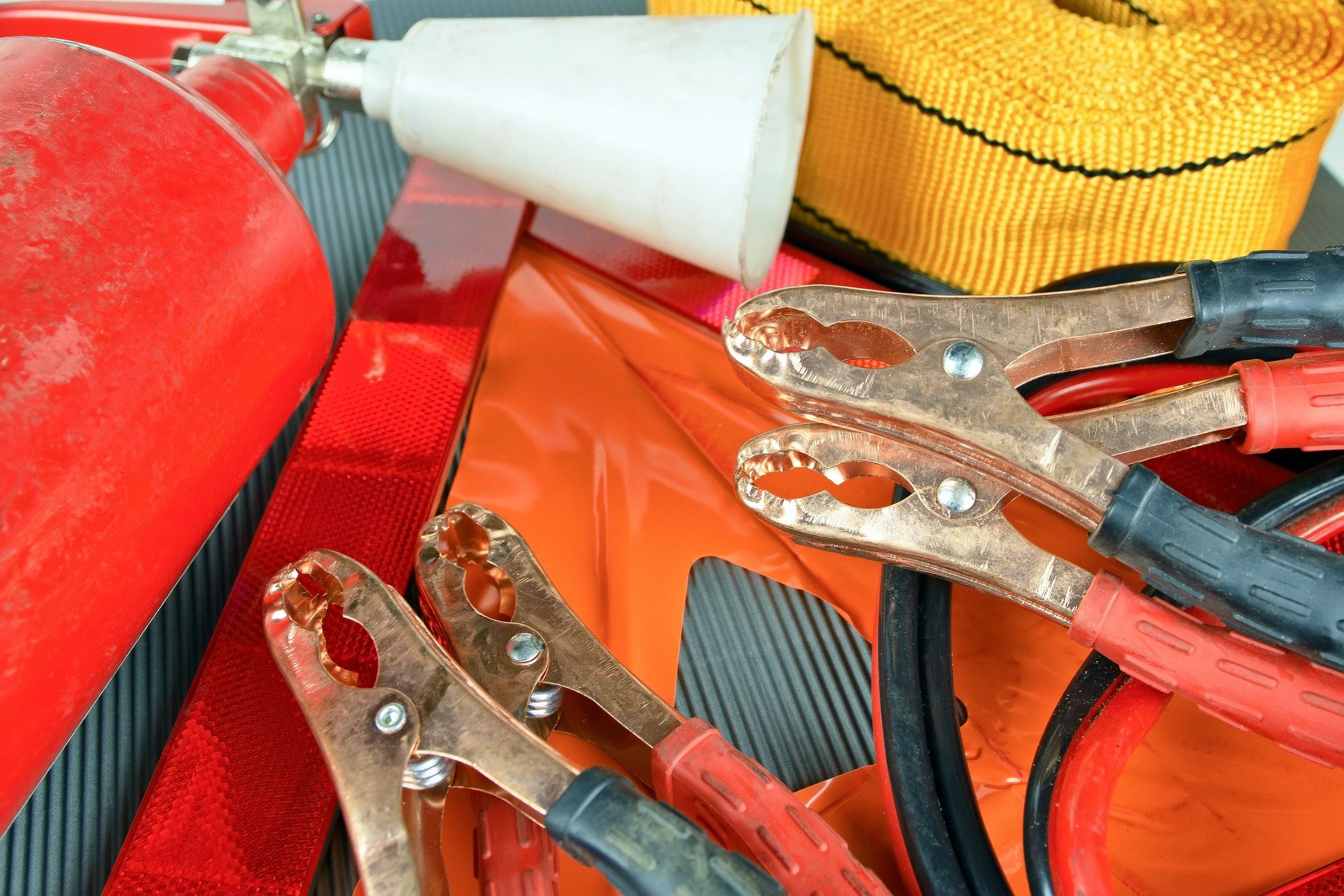 Towing and roadside emergency equipment including jumper cables and a tow strap
